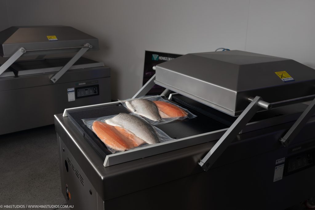 A Henkelman vacuum packaging machine with vacuumed sealed fish on it.