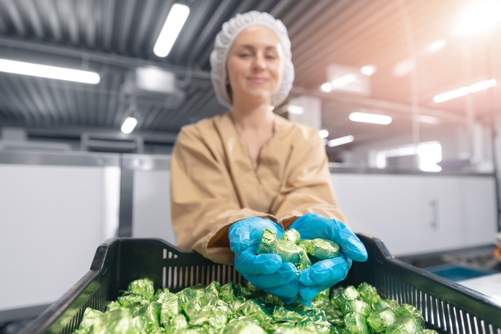 A food processing worker scooping fresh profuce in their gloved hands.